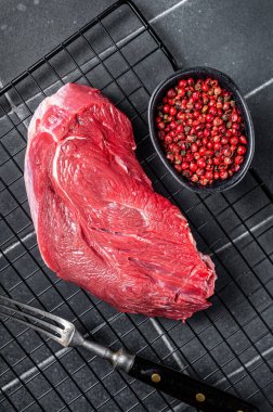 Raw beef meat piece for grilling with spices. Black background. Top view.
