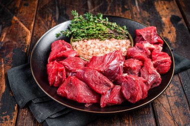 Raw lean diced casserole beef meat for cooking Goulash. Wooden background. Top view.