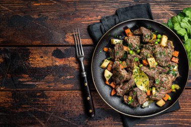 Beef meat stew, braised beef meat with vegetables in a plate. Wooden background. Top view. Copy space.