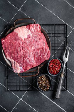 Raw piece of marble beef brisket meat with spices. Black background. Top view.