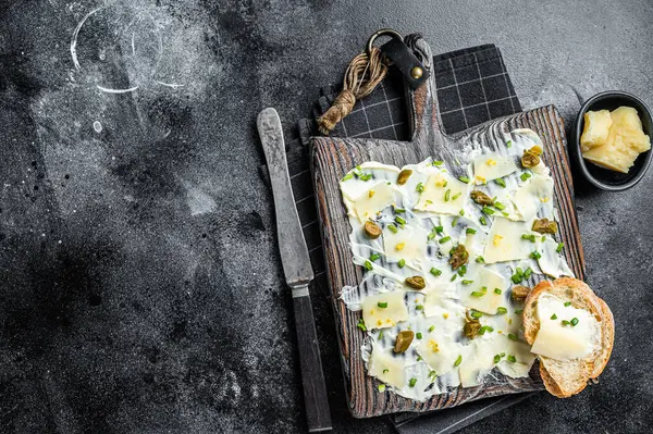 Butter board with herbs, lemon zest, capers, parmesan cheese and sea salt, Butterboard. Black background. Top view. Copy space.