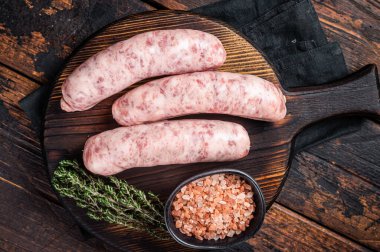Fresh Raw Bratwurst meat sausages ready for cooking on wooden board. Wooden background. Top view.