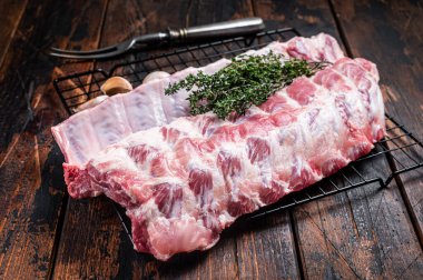 Raw pork spare ribs on a rack with herbs. Wooden background. Top view.