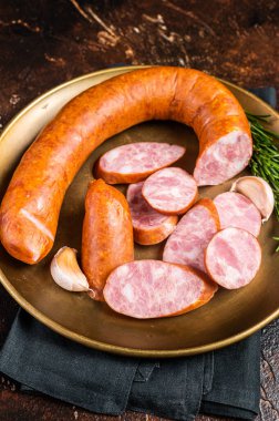 Polish Smoked sausage in a steel plate. Dark background. Top view.