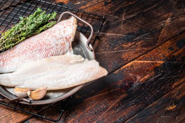Raw red perch fillet, redfish fish meat in a steel tray. Wooden background. Top view. Copy space.