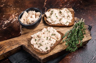 Cod Liver open Sandwich on wooden board. Dark background. Top view.