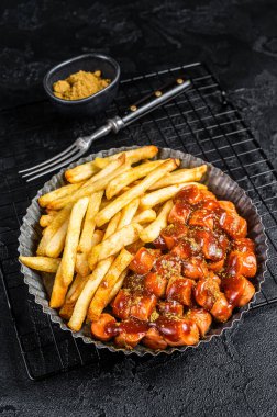 German fastfood currywurst meal, curry wurst with french fry. Black background. Top view.