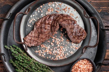 BBQ Grilled Machete or skirt beef meat steak in steel tray. Wooden background. Top view.