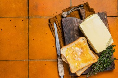 Kızarmış ekmeğe tereyağı sürüyorum. Turuncu arka plan. Üst Manzara. Boşluğu kopyala.