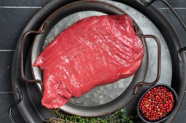 Fresh Raw flank beef meat steak and ingredients for cooking. Black background. Top view.