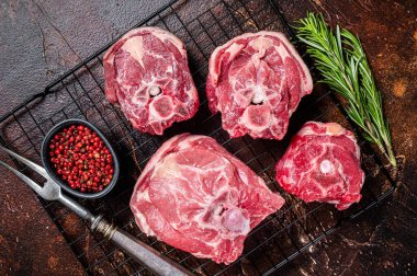 Fresh Raw lamb neck meat slices, mutton meat on a rack with herbs. Dark background. Top view.