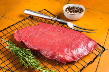 Raw flank beef meat steak ready for grilling. Orange background. Top view.