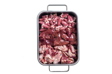 Çiğ tavuk eti, bağırsaklar, mideler, ciğer ve kalpler çelik tepside bitkilerle birlikte. İzole, beyaz arkaplan