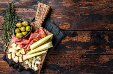 Cheese and meat plate, antipasti with Prosciutto ham, Parmesan, Blue cheese, Melon and Olives on wooden board. Wooden background. Top view. Copy space.