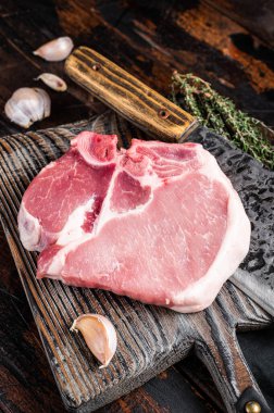 Butcher cutting board with Raw T-bone pork chop meat steak. Wooden background. Top view.