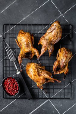 Grilled whole quails with herbs and spices. Black background. Top view.