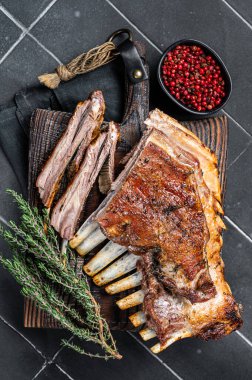 Grilled Rack of lamb ribs, mutton spareribs on wooden board. Black background. Top view.