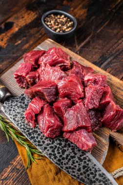 Sliced Raw venison dear meat for a stew, game meat on butcher cutting board. Wooden background. Top view.