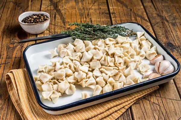 Raw Manti Dumpling with meat in tray with herbs and spices. Wooden background. Top view.