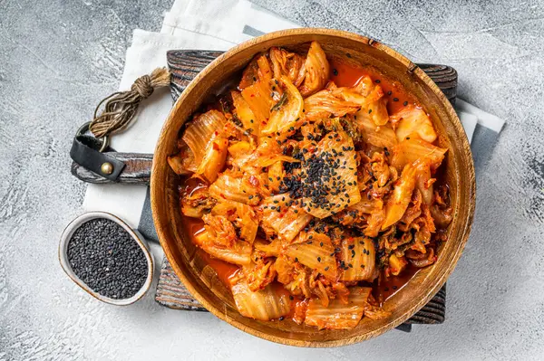 Kimchi cabbage in a wooden plate with chopsticks for eating , Korean cuisine. White background. Top view.