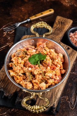 Turkish Menemen omelet with vegetabls and sucuk in askillet. Dark background. Top view.