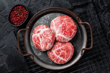 Raw pork cutlet, Crepinette with spices and herbs. Black background. Top view.