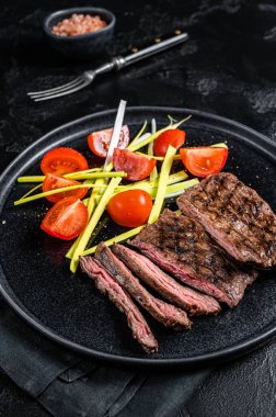 Grilled arrachera Skirt steak with garnish. Black background. Top view.