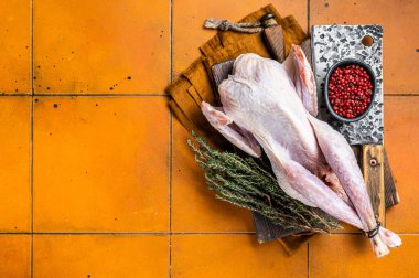 Farm Raw Guineafowl, guinea fowl with herbs ready for cooking. Orange background. Top view. Copy space. clipart