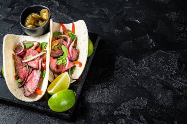 Biftek, kişniş, yeşil sos, jalapeno ve soğanlı Meksika bifteği. Siyah arka plan. Üst Manzara. Boşluğu kopyala.