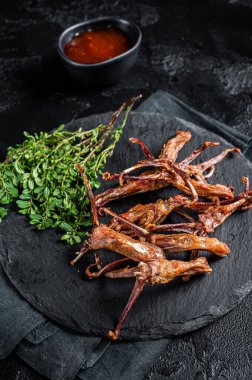 Cooked Spicy fried duck tongue. Black background. Top view.