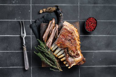 Grilled Rack of lamb ribs, mutton spareribs on wooden board. Black background. Top view.