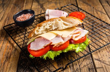 Sub sandwich with ham, cheese, tomato and Lettuce. Wooden background. Top view.
