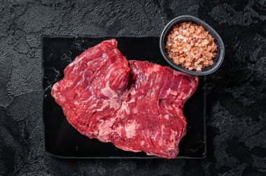 Skirt or Machete beef steak, raw meat ready for cooking. Black background. Top view.