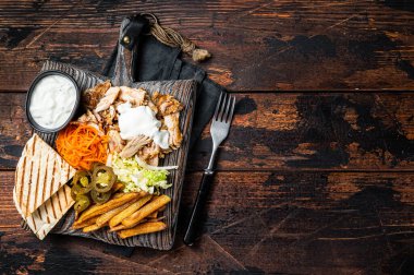 Kebab, Shawarma, Gyro grilled meat with french fries and vegetables on a wooden board. Wooden background. Top view. Copy space.