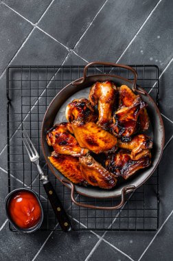 BBQ chicken wings in dip Barbecue sauce. Black background. Top view.