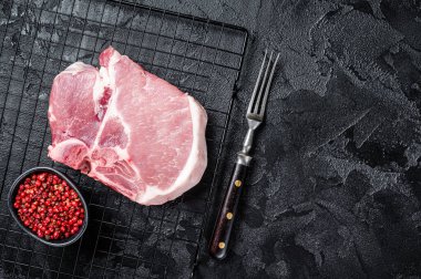 Pişmemiş çiğ domuz eti, ızgarada biftek. Siyah arka plan. Üst Manzara. Boşluğu kopyala.