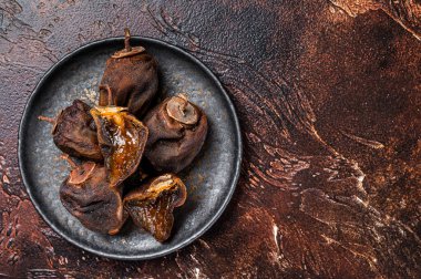 Tabakta kurutulmuş hurma meyvesi. Karanlık arka plan. Üst Manzara. Boşluğu kopyala.