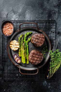 Grilled Fillet Mignon Steak with roasted asparagus. Black background. Top view.