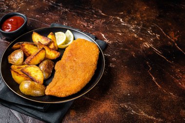 Roast pork schnitzel with fried potato, cooked meat steak. Dark background. Top view. Copy space.