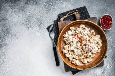 Manti Dumpling yoğurt ve domates sosuyla ahşap tabakta. Beyaz arka plan. Üst Manzara. Boşluğu kopyala.