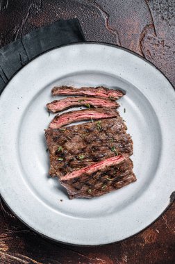 Homemade Cooked Skirt steak on a grill. Dark background. Top view.