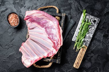 Butcher table with Rack of lamb, raw mutton ribs with meat cleaver. Black background. Top view.