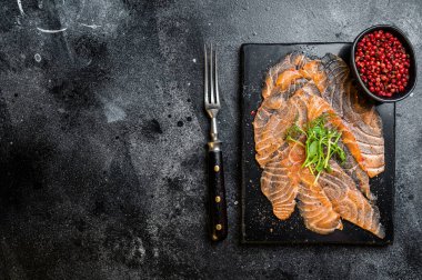 Salmon carpaccio with microgreens on marble board. Black background. Top view. Copy space.