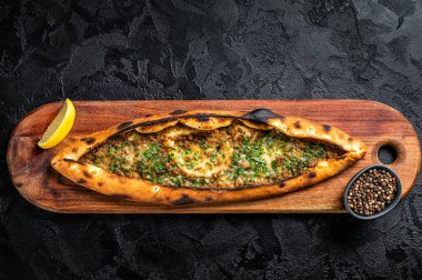 Turkish pide pie with beef meat and vegetables. Black background. Top view.