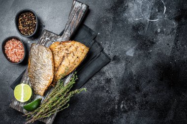 Tahtada otlu Gilthead Sea Bream filetosu kızart. Siyah arka plan. Üst Manzara. Boşluğu kopyala.