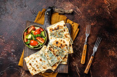 Freshly baked Turkish Gozleme, flatbread with greens and cheese. Dark background. Top view.