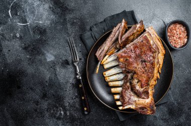 Roasted Rack of lamb ribs, mutton spareribs, sliced meat on plate. Black background. Top view. Copy space.