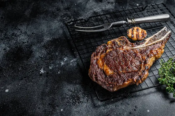 BBQ Grilled Tomahawk or rib eye with bone beef steak. Black background. Top view. Copy space.
