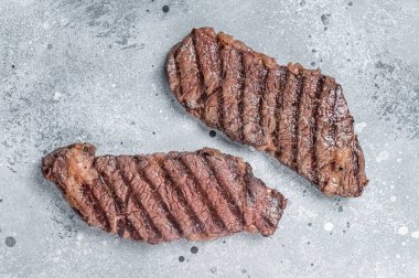 BBQ Grilled denver beef meat steak on a table. Gray background. Top view.