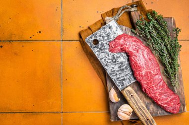 Taze çiğ pala bifteği ya da kasap kesim tahtasına asılmış yumuşak et. Turuncu arka plan. Üst Manzara. Boşluğu kopyala.